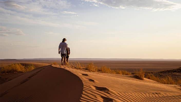 Twee manenn lopen op een duin